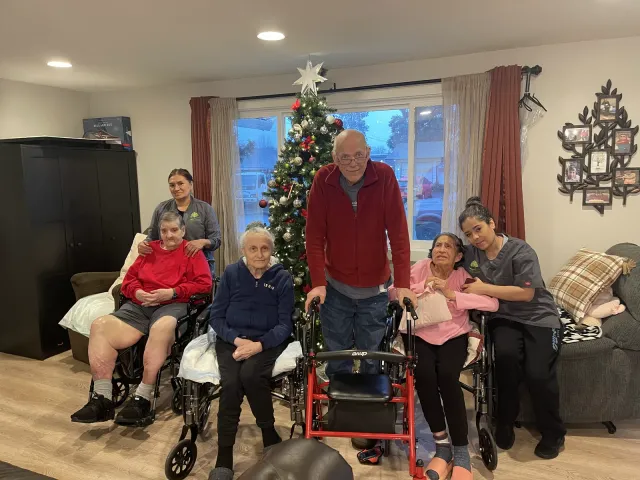 Residents and caregivers posed for a photo beside the Christmas tree in the living room.