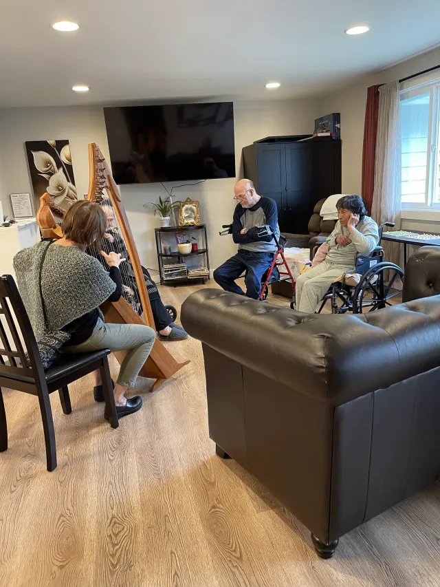 A harpist plays for residents in the living room.